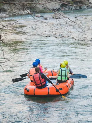 Tourists enjoying river rafting on Lidder river in Kashmir surrounded by mountains